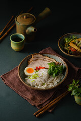 Asian noodle soup on table, ramen with pork, vegetables and egg in a bowl. Copy space