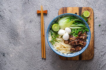 Japanese ramen soup with chicken, egg, chives and bok choy on concrete background.