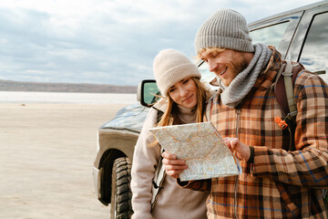 White couple smiling and examining map together during car trip