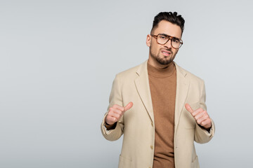 arrogant critic pointing at himself with thumbs isolated on grey.