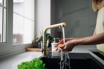 hands wash the egg under the faucet in the kitchen