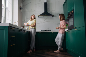 A lesbian couple is standing in the kitchen. One of the women cooks food, the other communicates with her