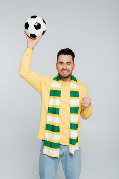excited sports fan holding soccer ball and showing win gesture isolated on grey.