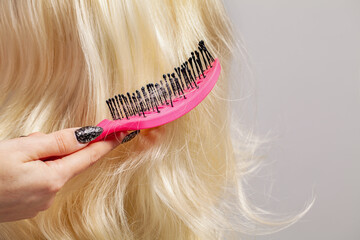 Hair care and hair loss concept. Long blonde hair and comb