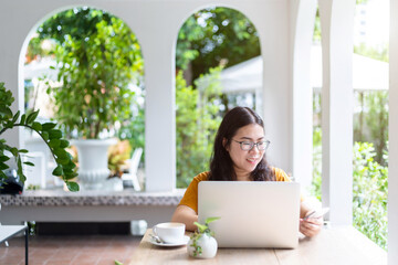 Happy of asian freelance people business female and writing message on smartphone working casual working with laptop computer with coffee cup in coffee shop like the background,communication concept