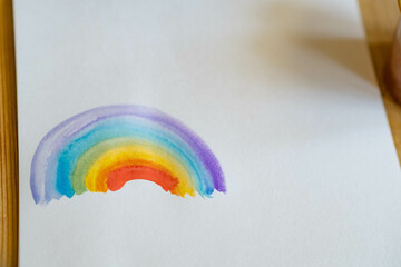 child drawing rainbow on white watercolor paper with place for text