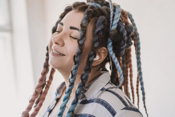 Emotional pretty young plus size woman with dreadlocks listens to music on headphones. nonconformist girl enjoys music in airpods