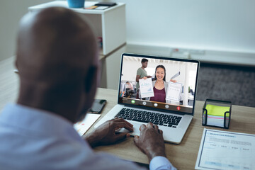 Smiling asian businesswoman showing graphs and reports to african american male colleague on laptop