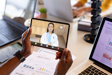 Cropped image of african american businessman video conferencing with female asian doctor in office - obrazy, fototapety, plakaty