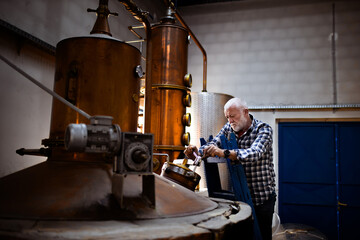 Male worker operating machinery in distillery. - obrazy, fototapety, plakaty