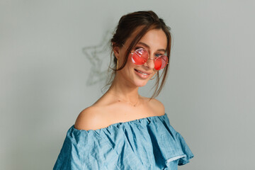 alluring european smiling girl with dark hair wearing round stylish glasses and blue shirt is...