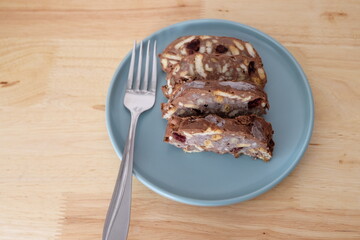 Homemade mosaic chocolate biscuit cake served in a blue plate, selective focus. It is called "Mozaik Pasta" in Turkish. That is texture of it not grain. Traditional Turkish dessert.