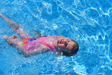 Pretty little girl smiles in swimming pool
