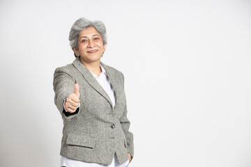 Portrait of a confident mature senior indian business woman in a suit do thumbs up isolated on...