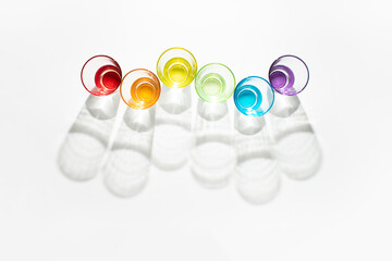 Minimal creative concept made with sunlit colorful glasses on white background. Vibrant rainbow aesthetic.