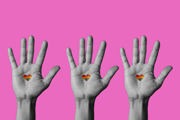 heart-shaped rainbow pride flag in raised hands