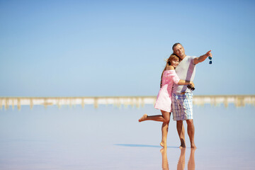 A man and a woman are walking along the beach together. Couple in love on the beach. A guy and a girl walk along the salt lake, pink lake
