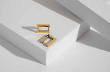 Rectangle golden earrings pair on white podium