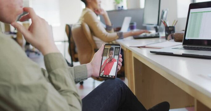 Caucasian businessman using smartphone for video call with african american business colleague