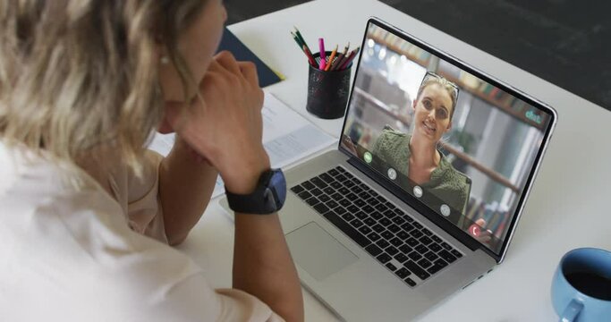 Caucasian businesswoman using laptop for video call with caucasian business colleague