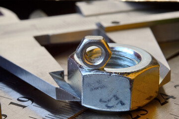 Accurate measuring tool caliper and metal ruler lie in place with nuts. close-up.