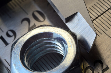 Accurate measuring tool caliper and metal ruler lie in place with nuts. close-up.