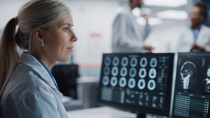 Medical Hospital Health Care Lab: Camera Captures Professional Neuroscientists Analysing CT Scan Finding Cure for Sick Patient and Female Neurologists Using Computer with Brain Scan MRI Images