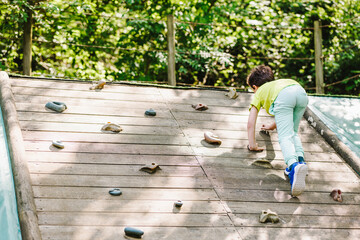 Anonymous child practicing climbing on wall on playground