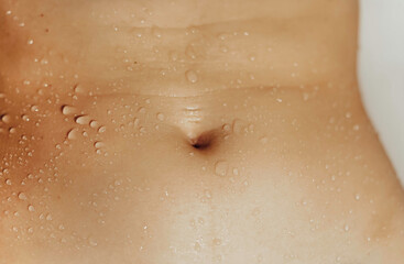 Close-up image of female beautiful slim belly with water drops. - obrazy, fototapety, plakaty