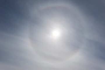 Round rainbow in a clear blue sky (sun halo), glowing cirrus and cumulus clouds. Nature,...