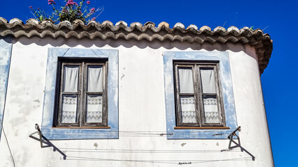 Facade of an antique house in a Portuguese village with two windows.