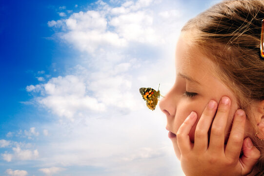 a child - a  girl with close eyes and dreamy expression with butterfly on nose over beautiful sky like a concept of imagination, dreaming and bright future - Powered by Adobe