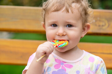 Baby eats a lollipop in the park. Selective focus.
