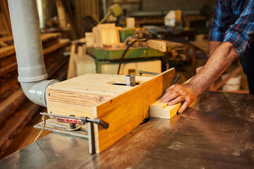 Senior carpenter in uniform works on a woodworking machine at the carpentry manufacturing
