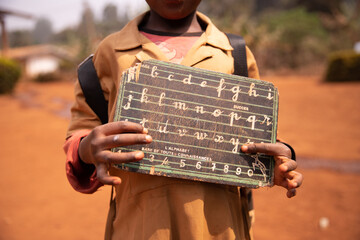 African child shows his blackboard with alphabet and the numbers engraved on it. Educational concept