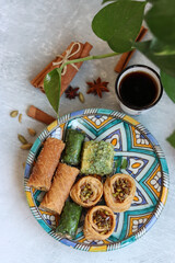Arabian sweets on a plate. Traditional pastries made of pistachio and honey syrup. Baklava texture close up. Mediterranean cuisine receipts. 
