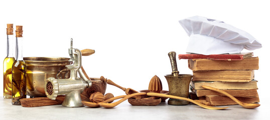 Chef's hat, vintage cookbooks, and old kitchen utensils isolated on  white.