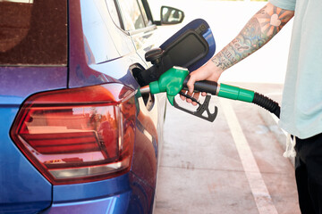 Close-up shot of a man with a tattoo pumping gasoline