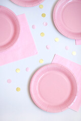 Pink paper disposable plates, napkins and straws for drinks on white background. Table setting for picnic. Bright eco-court. Birthday, party and holiday concept. Top view, flat lay