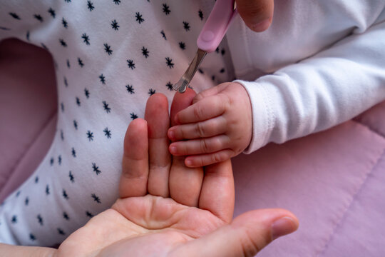 Mano de bebé agarrada a mano de mamá preparada cara cortar uñas
