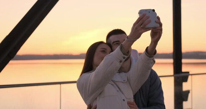 A guy and a girl in love are photographed on a Polaroid. Sunset.