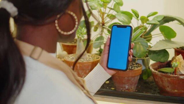 Forist African American woman holding phone with chroma key. Greenhouse worker female botanist, small business owner. Gardener working in flower shop, plant store. 