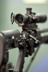 Detail view of the telescope part of a military weapon sniper placed on a tripod. Army weapons industry.
