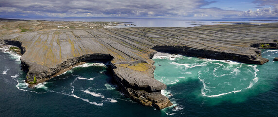 The Black fort by the ocean and cliffs and rugged stone terrain of Aran Island. Warm sunny day and...