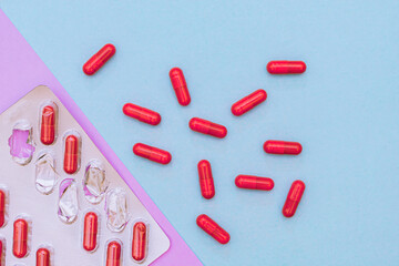 Red pills in capsules on a blue background - obrazy, fototapety, plakaty