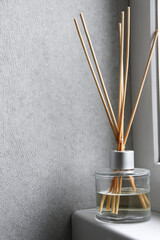 Reed diffuser on windowsill near light wall