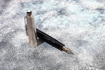 Fountain pen on a marble and gray background. Selective focus.