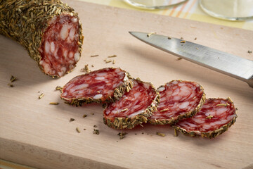 Traditional French sausage and slices covered with herb de provence on a cutting board close up 