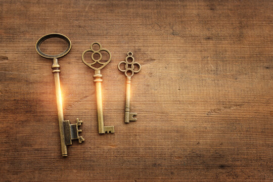 Top view image of old keys with golden light over wooden background
