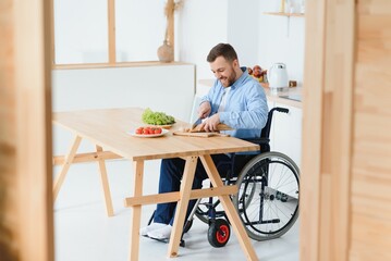 man in a wheelchair cuts vegetables in the kitchen